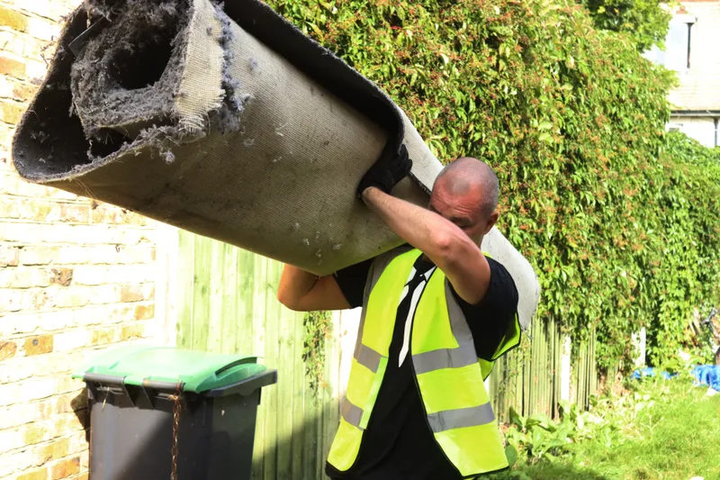 man and van clearance compamny carrying rolled up carpet for carpet disposal